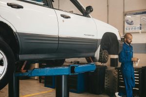 white Subaru Forester on a car lift with a mechanic nearby