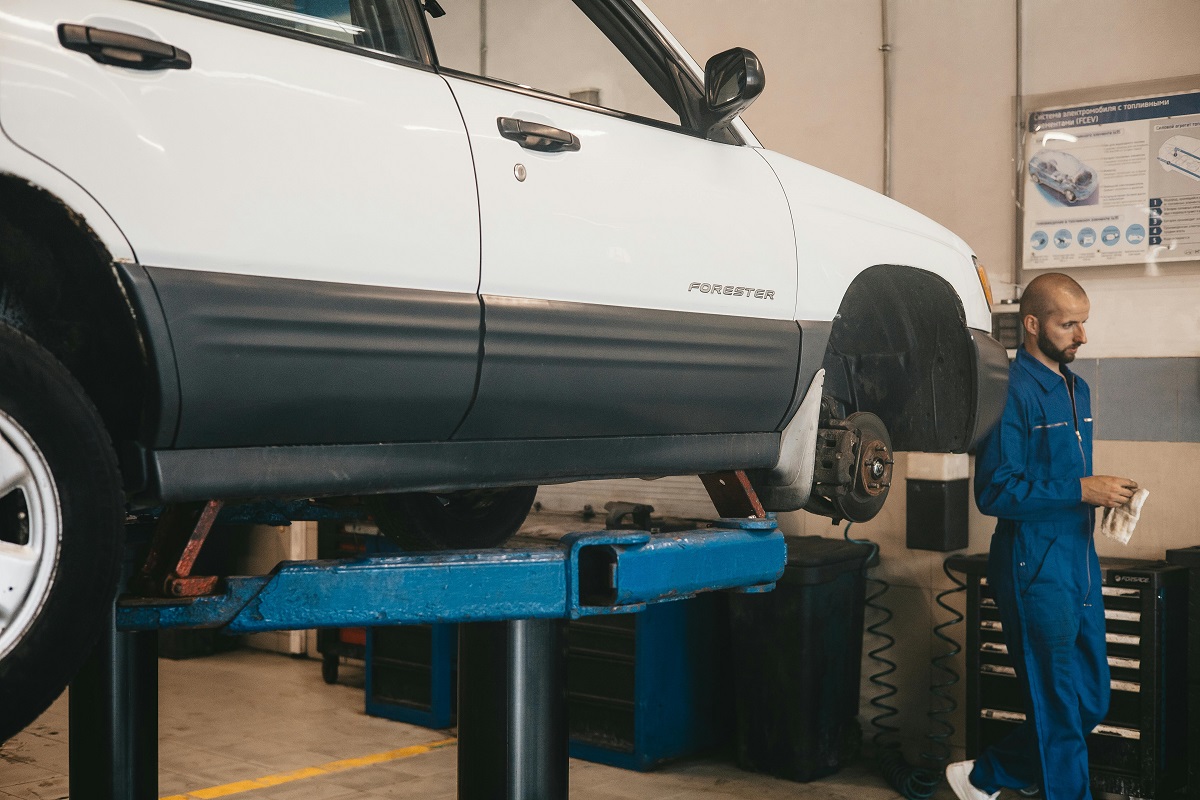 white Subaru Forester on a car lift with a mechanic nearby