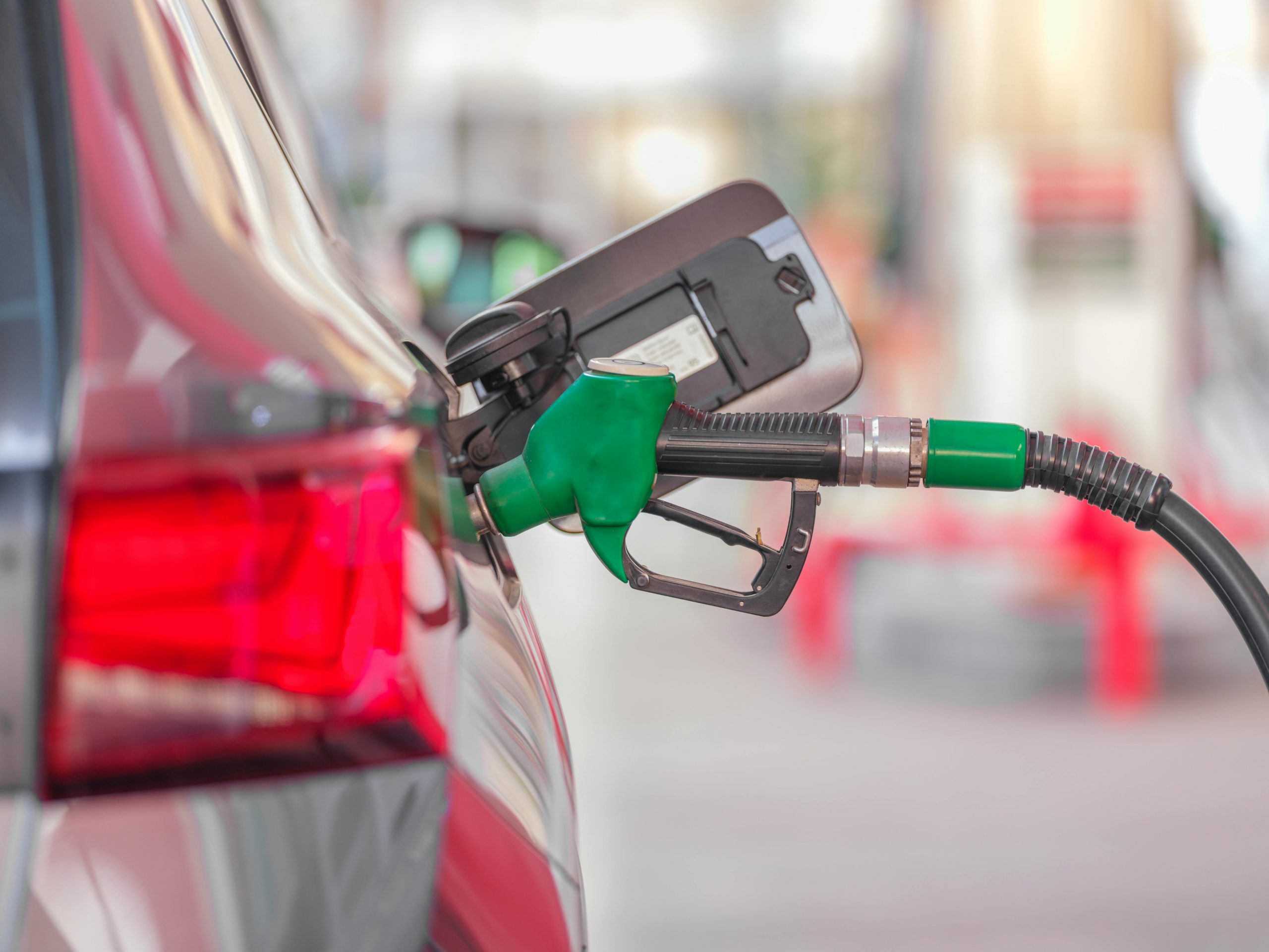 green fuel nozzle inserted into a car's gas tank