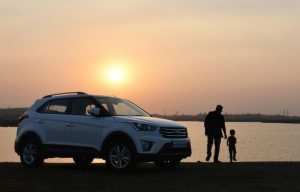 hyundai flex fuel car parked near the sea, with silhouettes of a father and son standing beside it