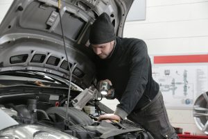 mechanic inspecting the engine of a car with the hood open