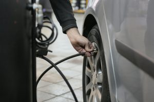 close-up of a hand checking the tire pressure of a silver car with a pressure gauge