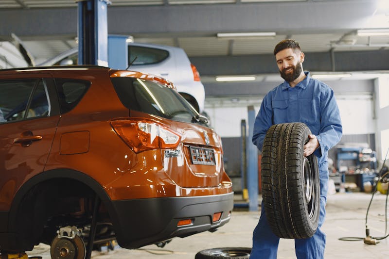 a mechanic carrying a tire